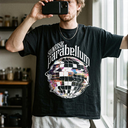 May include: A black short-sleeve t-shirt featuring the white text "SUNRISE parabellum" arched over a graphic of a distorted, checkered disco ball with colorful, glitch-like pixelated accents throughout the sphere design.