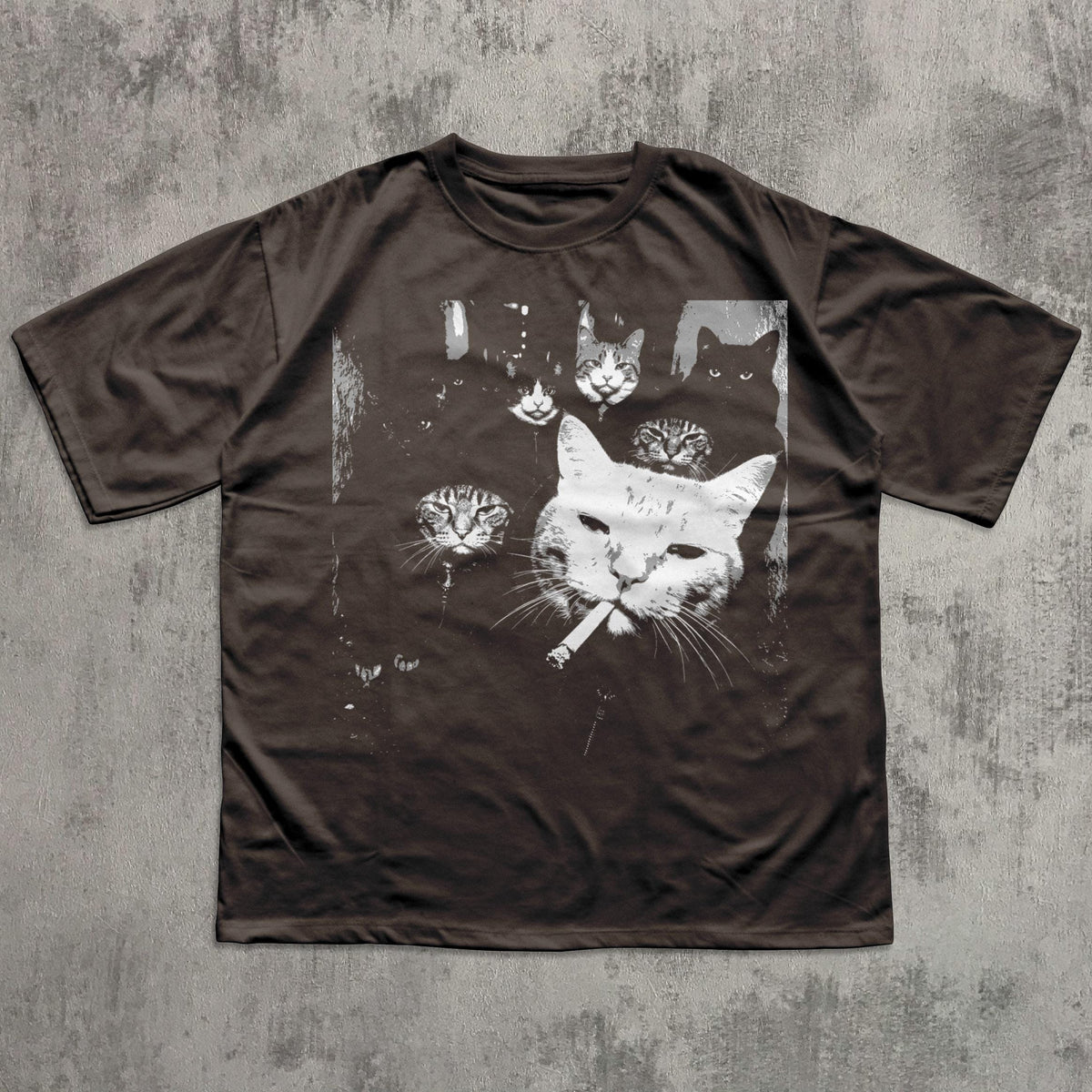 May include: Dark brown t-shirt featuring a graphic of several cat faces, with one cat smoking a cigarette. The cats are depicted in white against a dark background. The shirt has short sleeves and a crew neck.