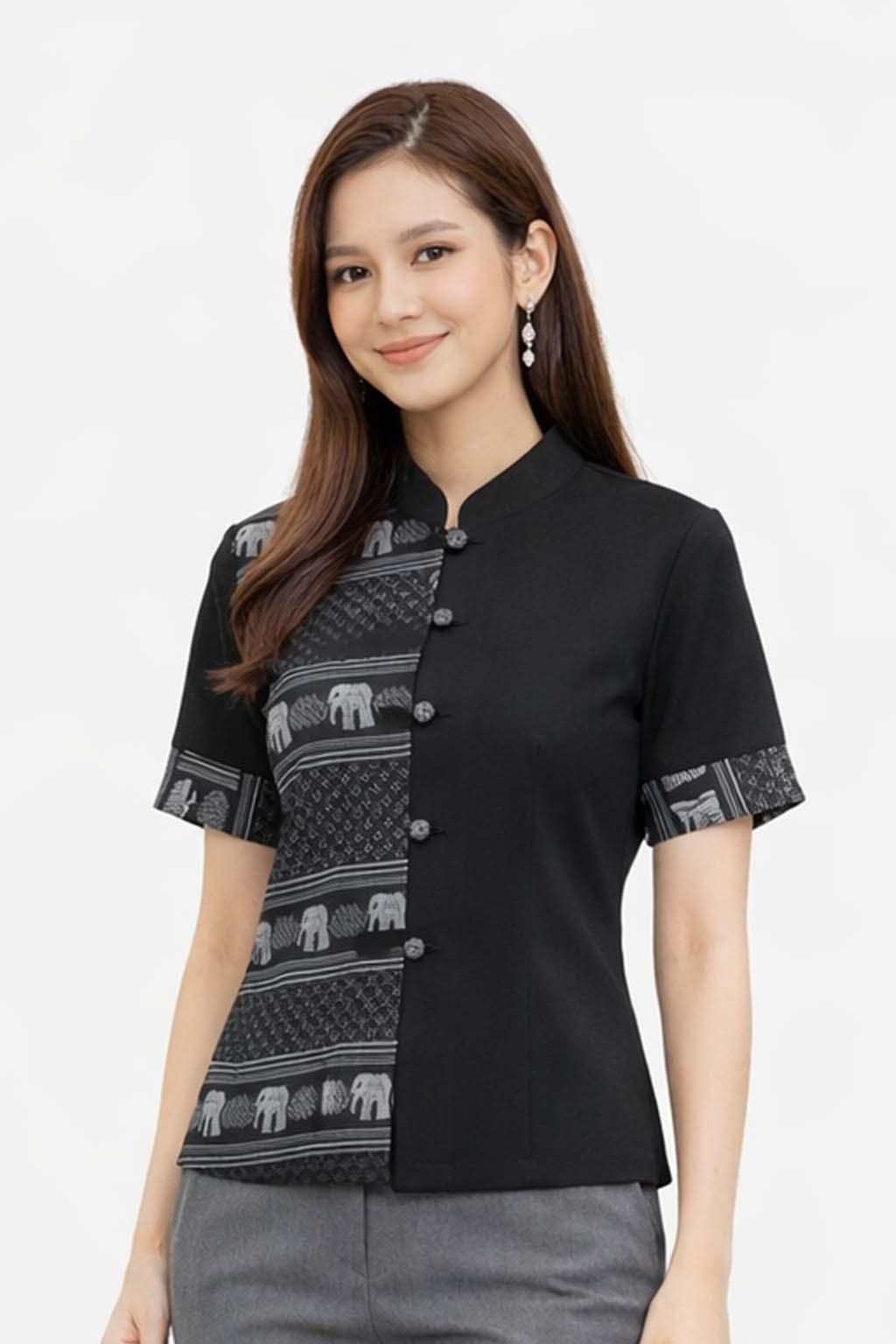 May include: Black short-sleeved blouse with a mandarin collar and decorative buttons. The left side features a patterned design with elephants in gray and white. The sleeves also have a matching patterned trim. The blouse is paired with gray pants.