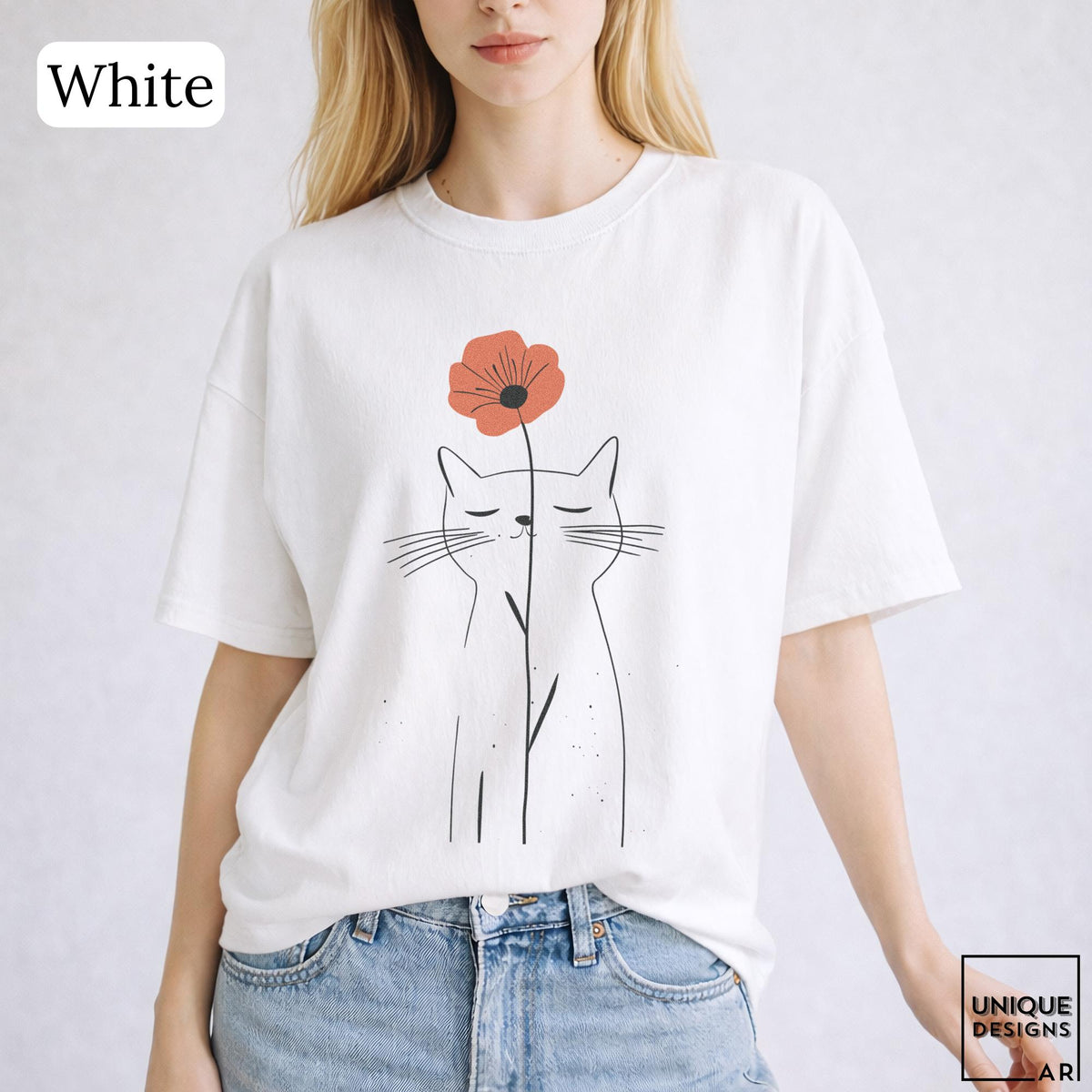 May include: A white short-sleeve t-shirt featuring a black line art illustration of a cat with closed eyes. A single orange flower is positioned above the cat's head, with its stem extending downward. The text "White" appears in the top left corner.