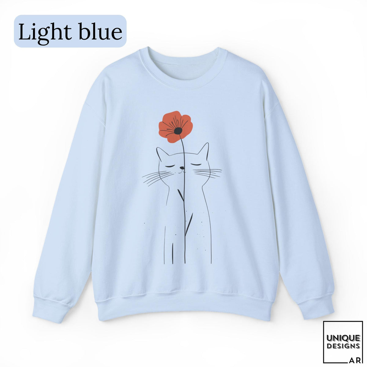 May include: A light blue crewneck sweatshirt featuring a minimalist black line drawing of a cat with closed eyes. A single orange poppy flower is positioned directly above the cat's head. The text "Light blue" appears in the top left corner.