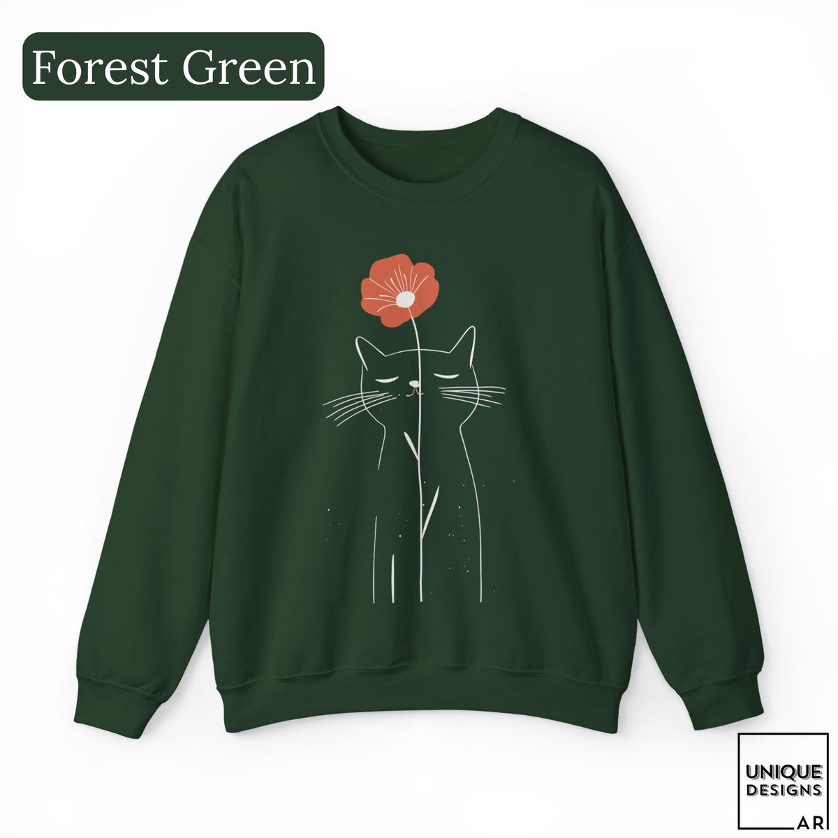 May include: A forest green crewneck sweatshirt featuring a white line art illustration of a cat with closed eyes. A single orange flower is positioned above the cat's head. The text Forest Green appears in the top left corner and Unique Designs AR in the bottom right.