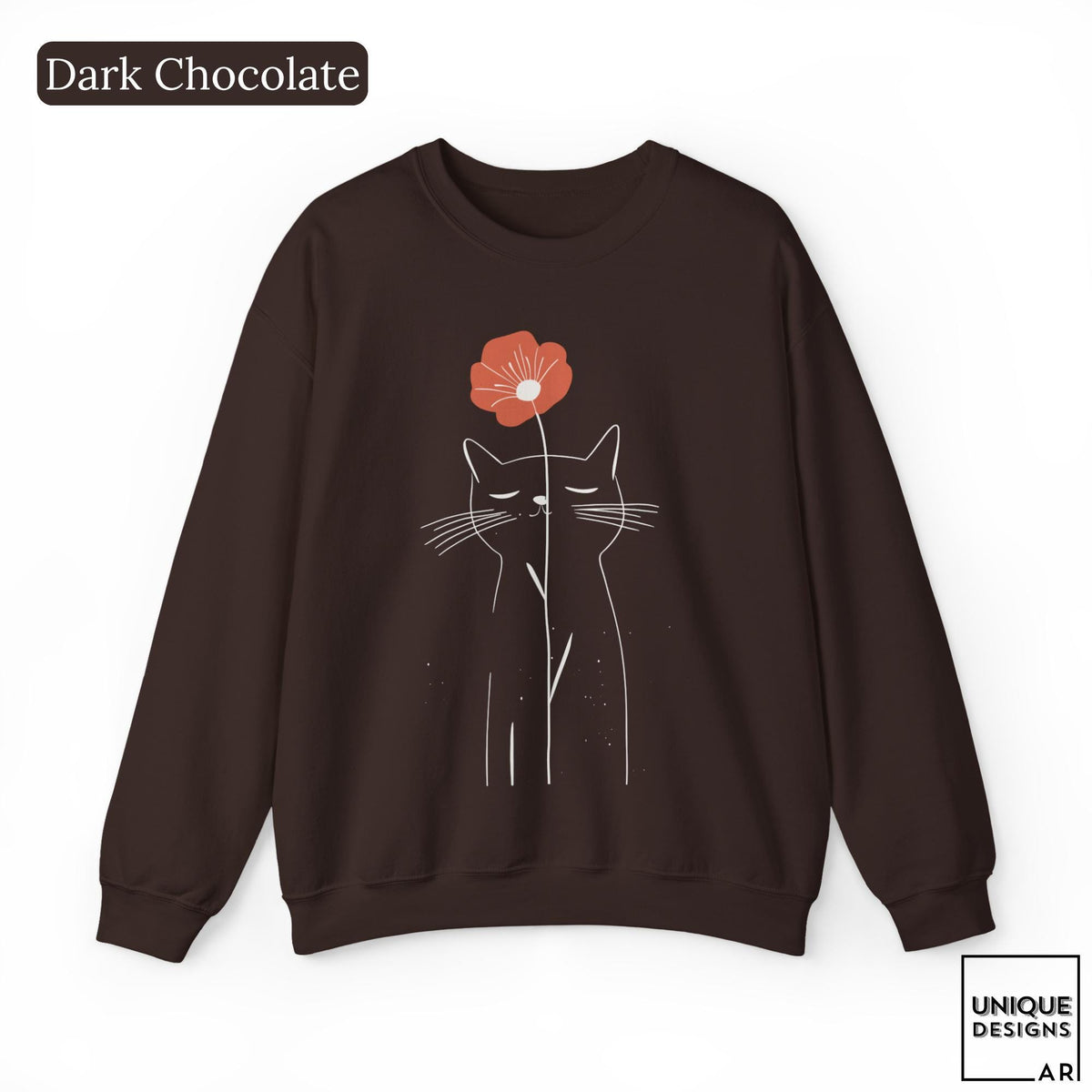 May include: A dark chocolate brown crewneck sweatshirt featuring a white line art illustration of a cat with closed eyes. A single orange-red flower is positioned above the cat's head. The text "Dark Chocolate" appears in the top left corner.