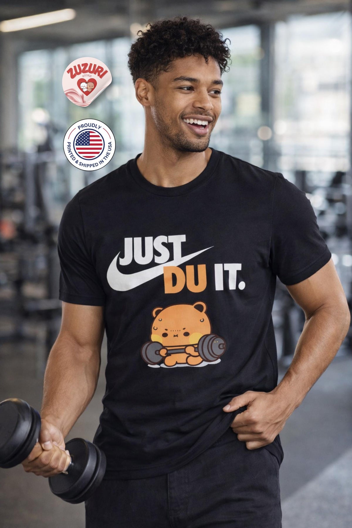 May include: Black t-shirt with the text "JUST DU IT." in white and orange. Below the text is a cartoon bear lifting weights. The image also includes two stickers with text and a US flag.