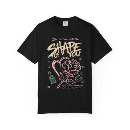 Shape of You” text with heart and rose illustration, music icons and pastel accents printed on a Comfort Colors oversized T-shirt.