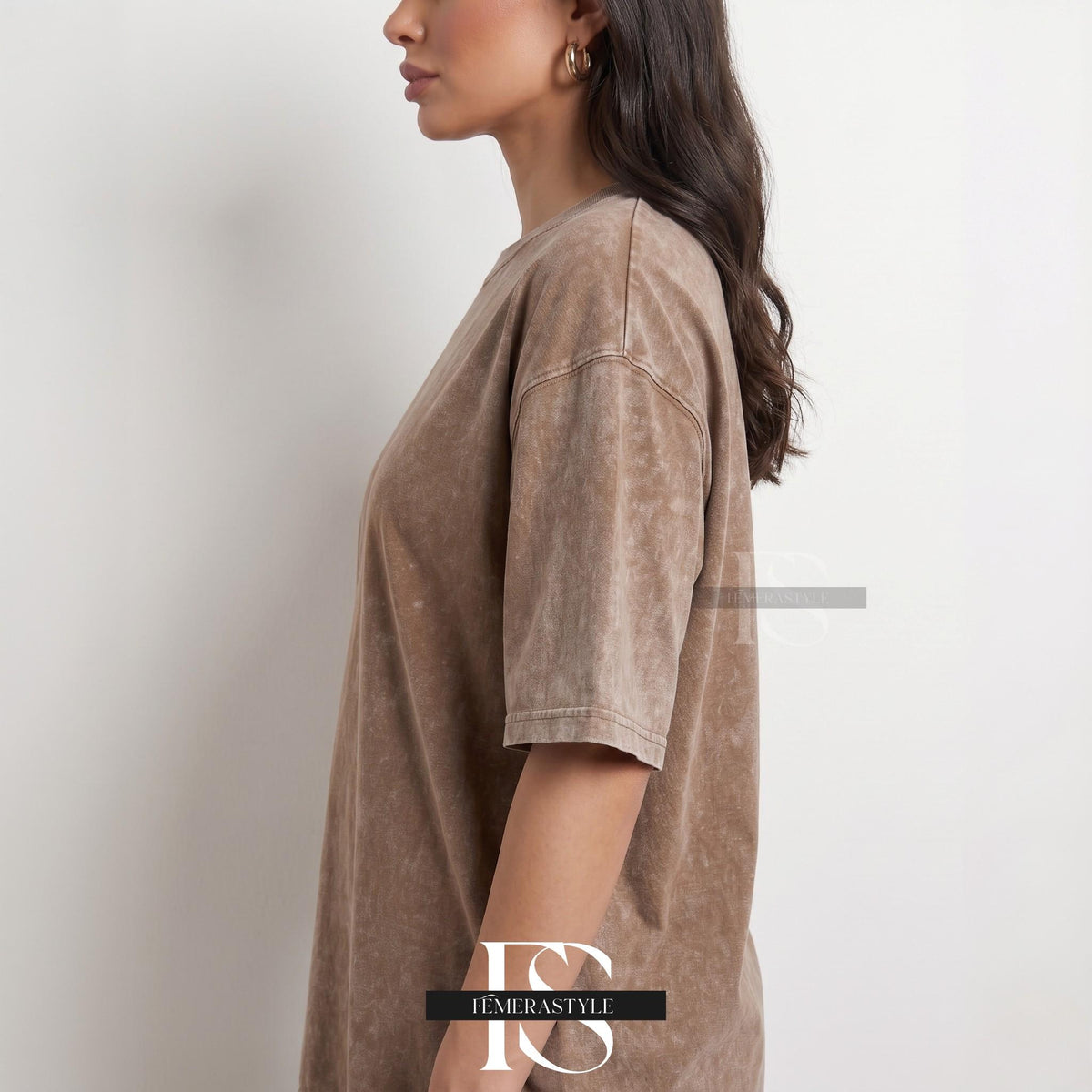 May include: A brown, oversized t-shirt with short sleeves. The shirt has a textured, faded appearance. The image shows the side view of the shirt on a person.