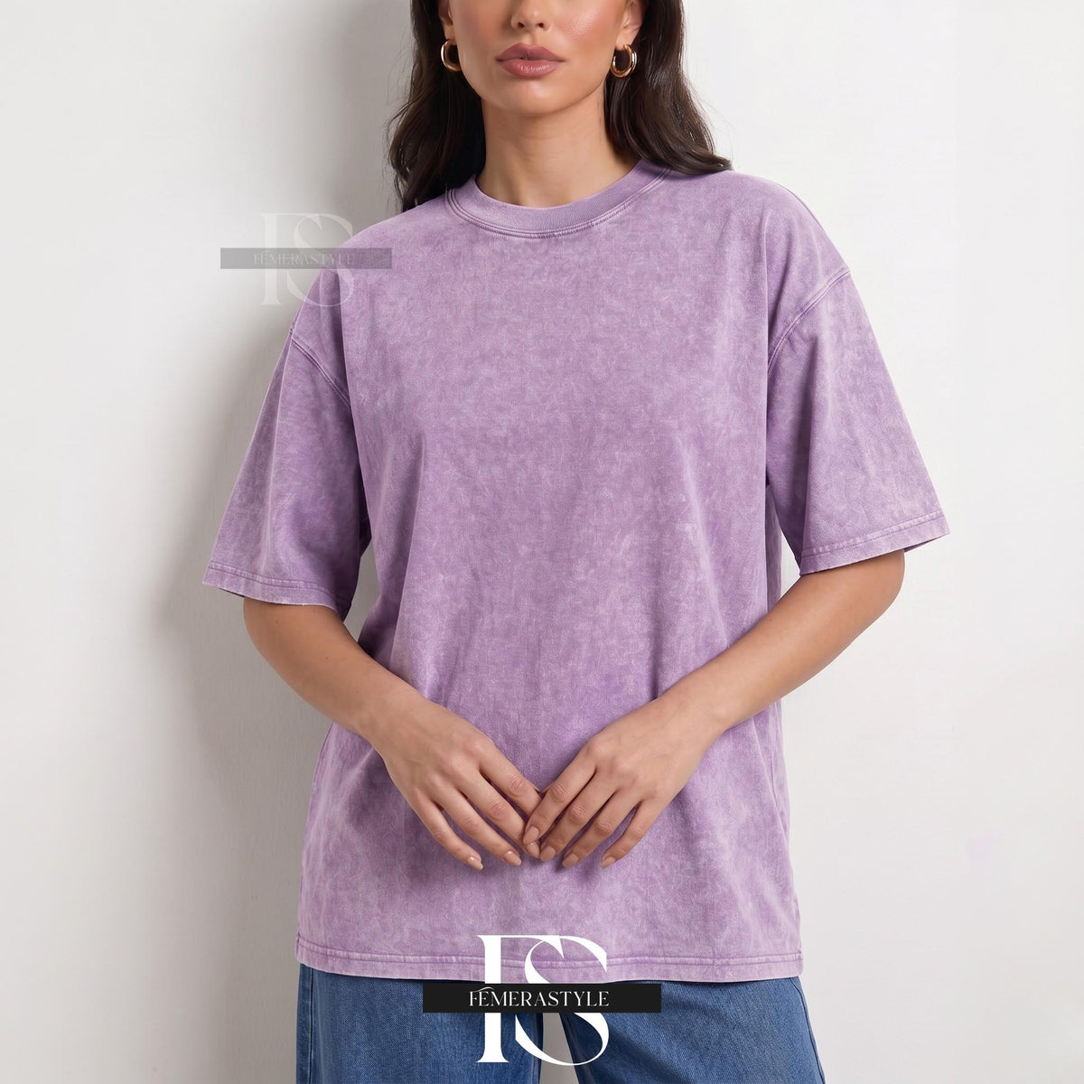 May include: A lavender-colored, short-sleeved t-shirt with a crew neck. The shirt has a slightly faded, textured appearance. The model is wearing blue jeans. The brand name "IEMERASTYLE" is visible at the bottom of the image.