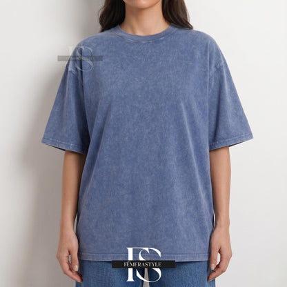 May include: A blue, short-sleeved t-shirt with a textured, faded appearance. The shirt has a crew neck and a relaxed fit. The model is wearing blue jeans. The shirt is from the brand Iemerastyle.