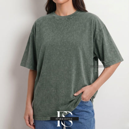 May include: A washed-out olive green t-shirt with a crew neck and short sleeves. The shirt has a slightly oversized fit and a textured appearance. The model is wearing blue jeans. The logo "IEMERASTYLE" is visible at the bottom.