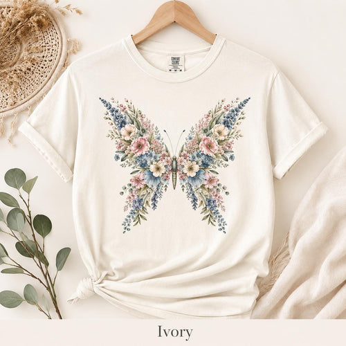 Woman wearing a Comfort Colors floral butterfly shirt with a pastel botanical flower design, styled in a cozy cottagecore setting, perfect as a nature lover gift or butterfly lover tee.
