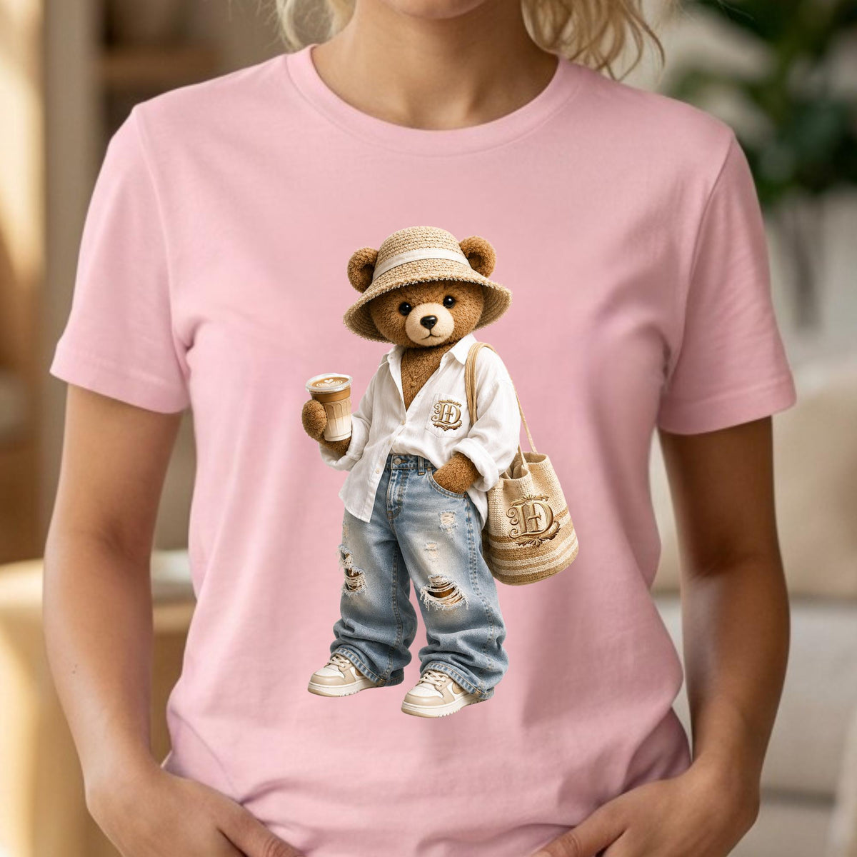May include: Pink t-shirt featuring a cartoon teddy bear wearing a straw hat, white shirt, ripped jeans, and sneakers. The bear is holding a coffee cup and a beige tote bag with a letter "H" on it.