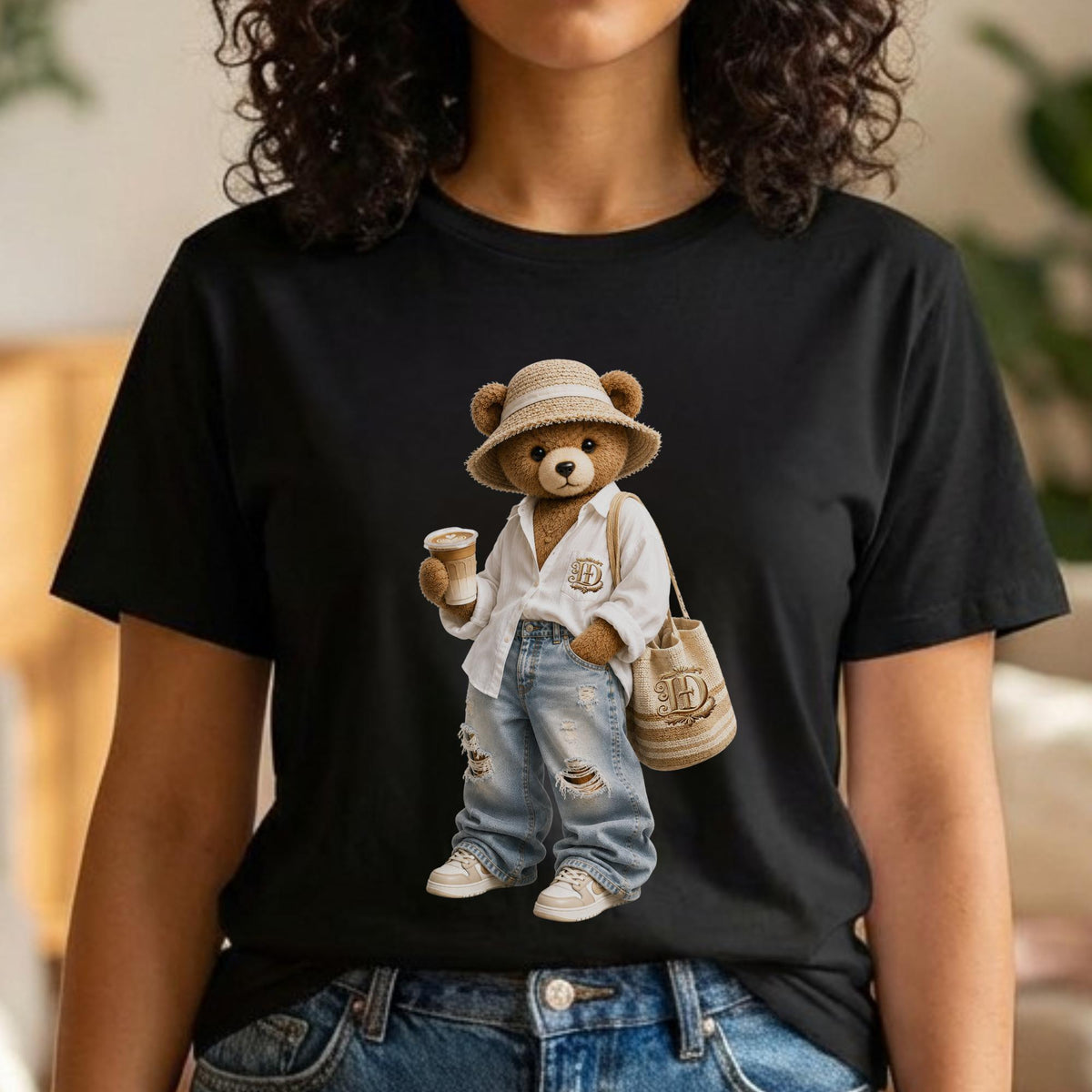 May include: Black t-shirt featuring a cartoon bear wearing a straw hat, white shirt, ripped jeans, and sneakers. The bear is holding a coffee cup and a tote bag. The tote bag and shirt have a monogram design.