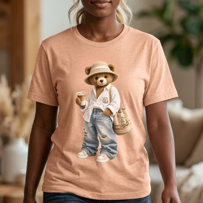 May include: Peach-colored t-shirt featuring a cartoon teddy bear wearing a straw hat, white shirt, ripped jeans, and sneakers. The bear holds a coffee cup and a tote bag. The bear's outfit is detailed with a logo.