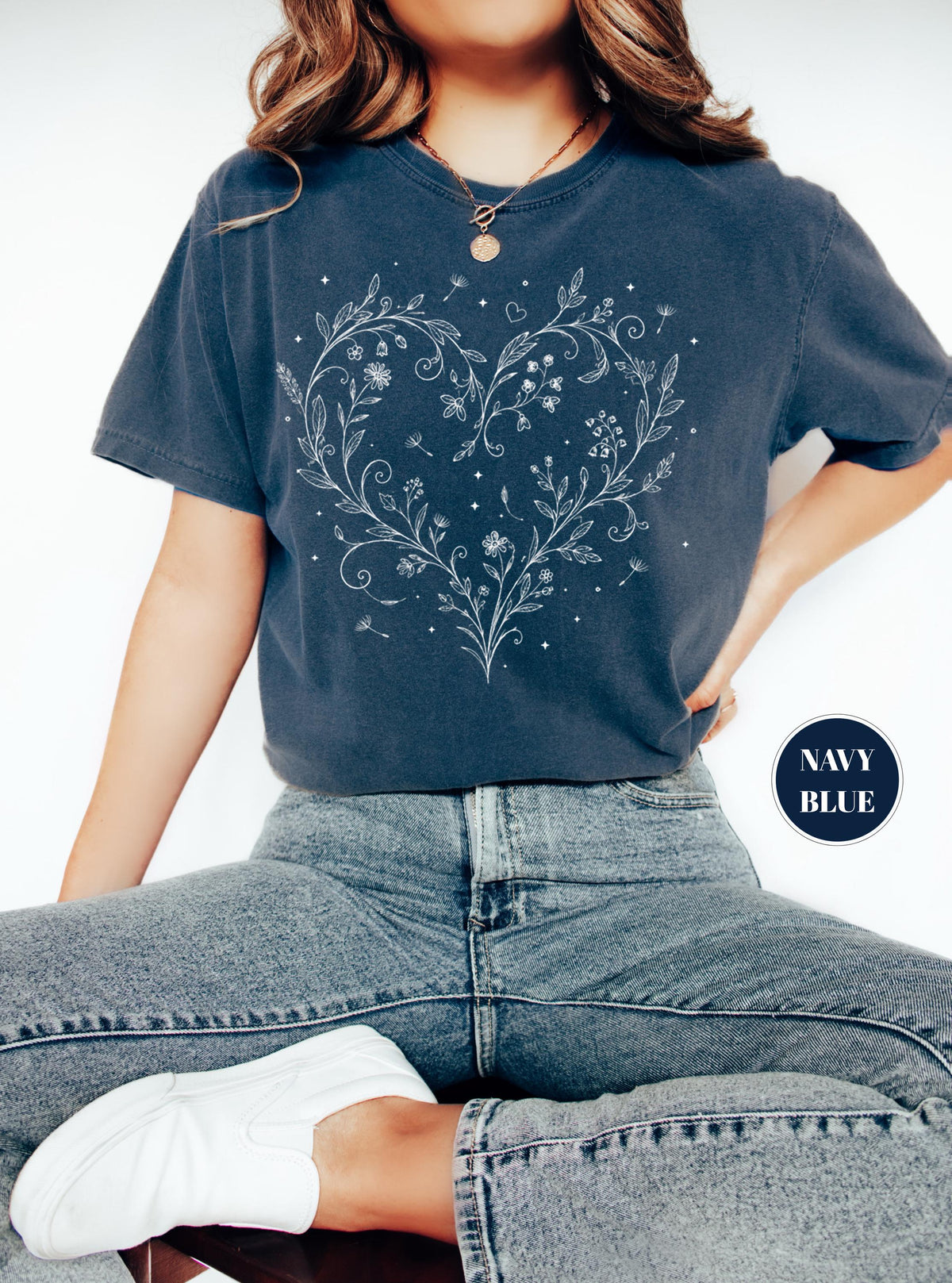 May include: Navy blue t-shirt featuring a white floral heart design. The design includes flowers, leaves, and small details. The shirt is a solid navy blue color. The text "NAVY BLUE" is in a navy blue circle.
