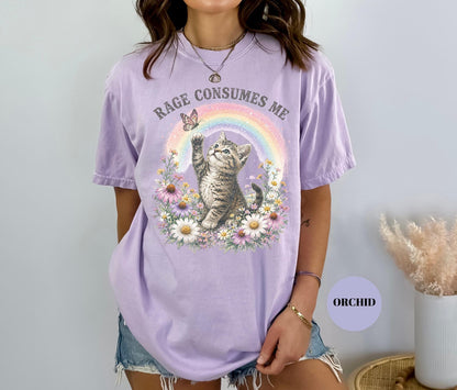 May include: A light purple t-shirt with the text "RAGE CONSUMES ME" above a graphic of a kitten reaching for a butterfly near a rainbow. The kitten is surrounded by flowers.