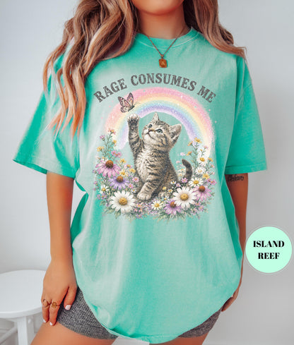 May include: A turquoise t-shirt featuring a graphic of a kitten reaching for a butterfly in front of a rainbow. The words "RAGE CONSUMES ME" are arched above the rainbow. The kitten is surrounded by flowers.