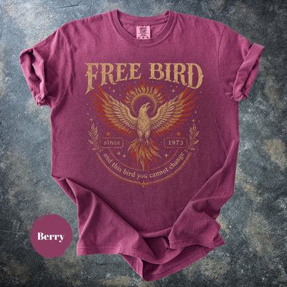 May include: Berry-colored t-shirt with a distressed graphic of a phoenix and the words "FREE BIRD" above it. The design includes the text "since 1973" and "and this bird you cannot change". The shirt has short sleeves and a crew neck.