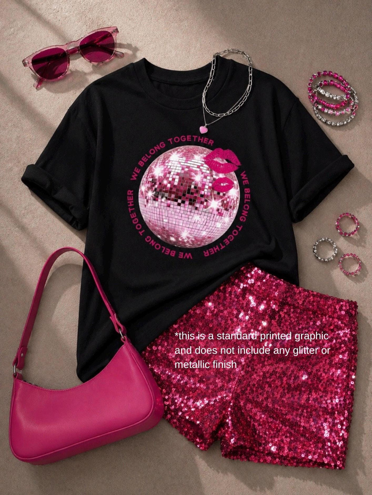 May include: A black t-shirt with a pink disco ball graphic, lip print, and the text WE BELONG TOGETHER, paired with pink sequin shorts, a pink shoulder bag, pink sunglasses, a silver chain necklace with a heart charm, and several pink rings.