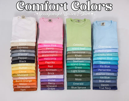 May include: Stacks of folded Comfort Colors heavyweight unisex t-shirts in various colors. The image displays a range of hues, including white, pink, green, and blue, with color names listed below each stack. The text "Comfort Colors" is at the top.