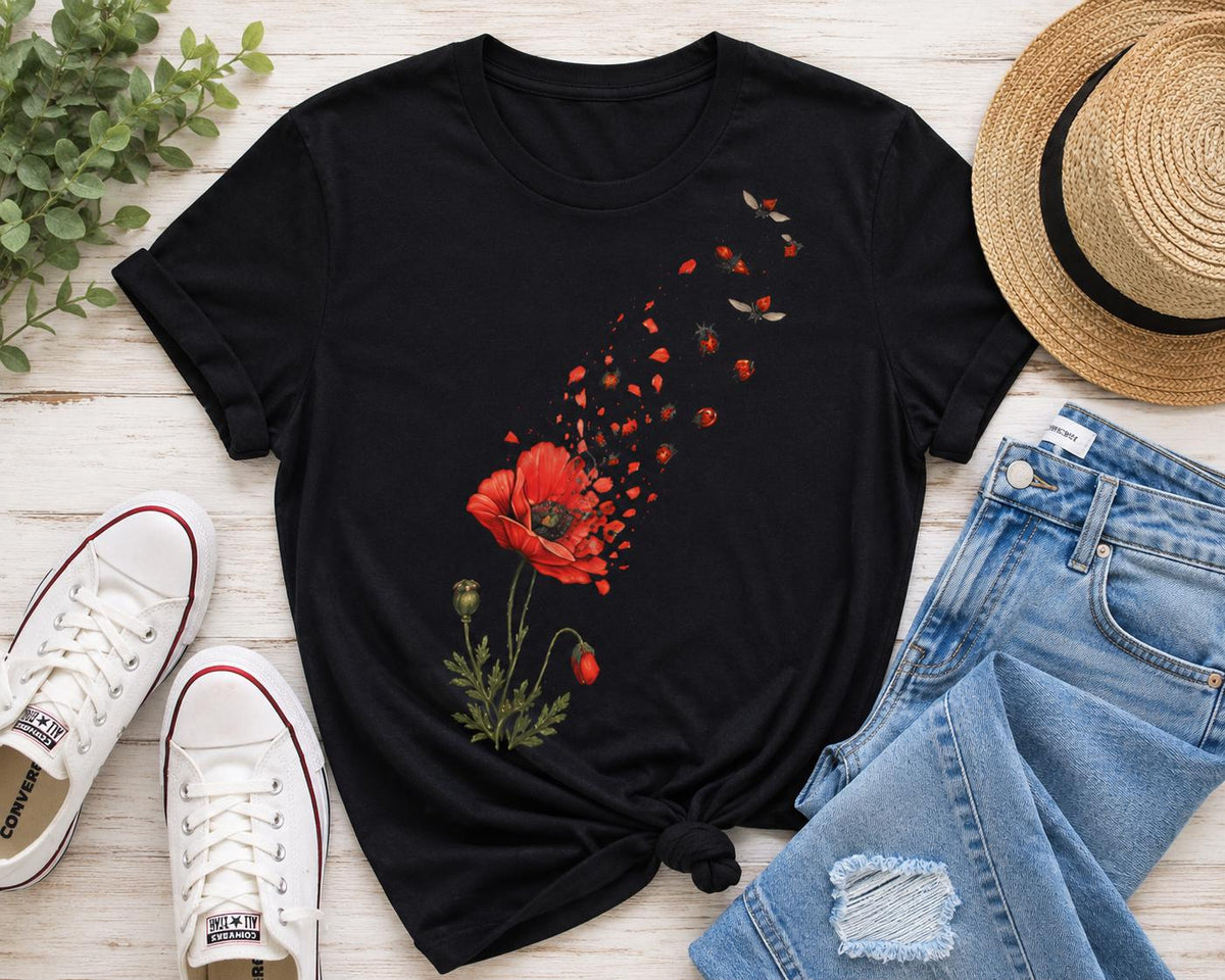 May include: A black short-sleeved t-shirt featuring a graphic print of a red poppy flower with petals that appear to be disintegrating and floating upward into the air, accompanied by small flying insects near the top of the design.