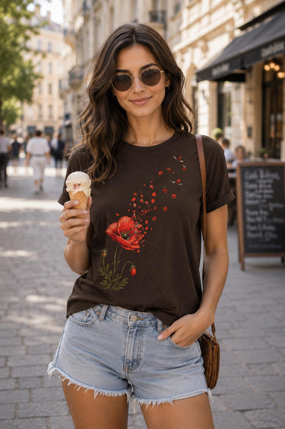 May include: A dark brown short-sleeved t-shirt featuring a graphic print of a vibrant red poppy flower with petals appearing to drift upward and away. The shirt has a crew neckline and rolled sleeves, paired with light blue denim shorts.