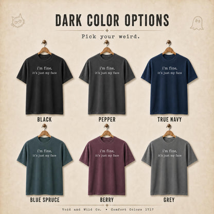 May include: Six short-sleeve t-shirts in black, pepper, true navy, blue spruce, berry, and grey. Each shirt features the white text 'i'm fine, it's just my face' centered on the chest. The image includes the text 'DARK COLOR OPTIONS' and 'Pick your weird.'