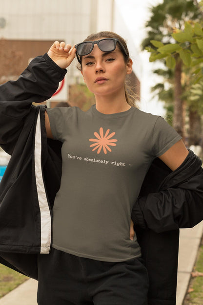 May include: A dark olive green short-sleeved t-shirt featuring a peach-colored stylized flower graphic centered on the chest. Below the flower, the text reads "You're absolutely right -" in a white, typewriter-style font. The shirt has a crew neckline.