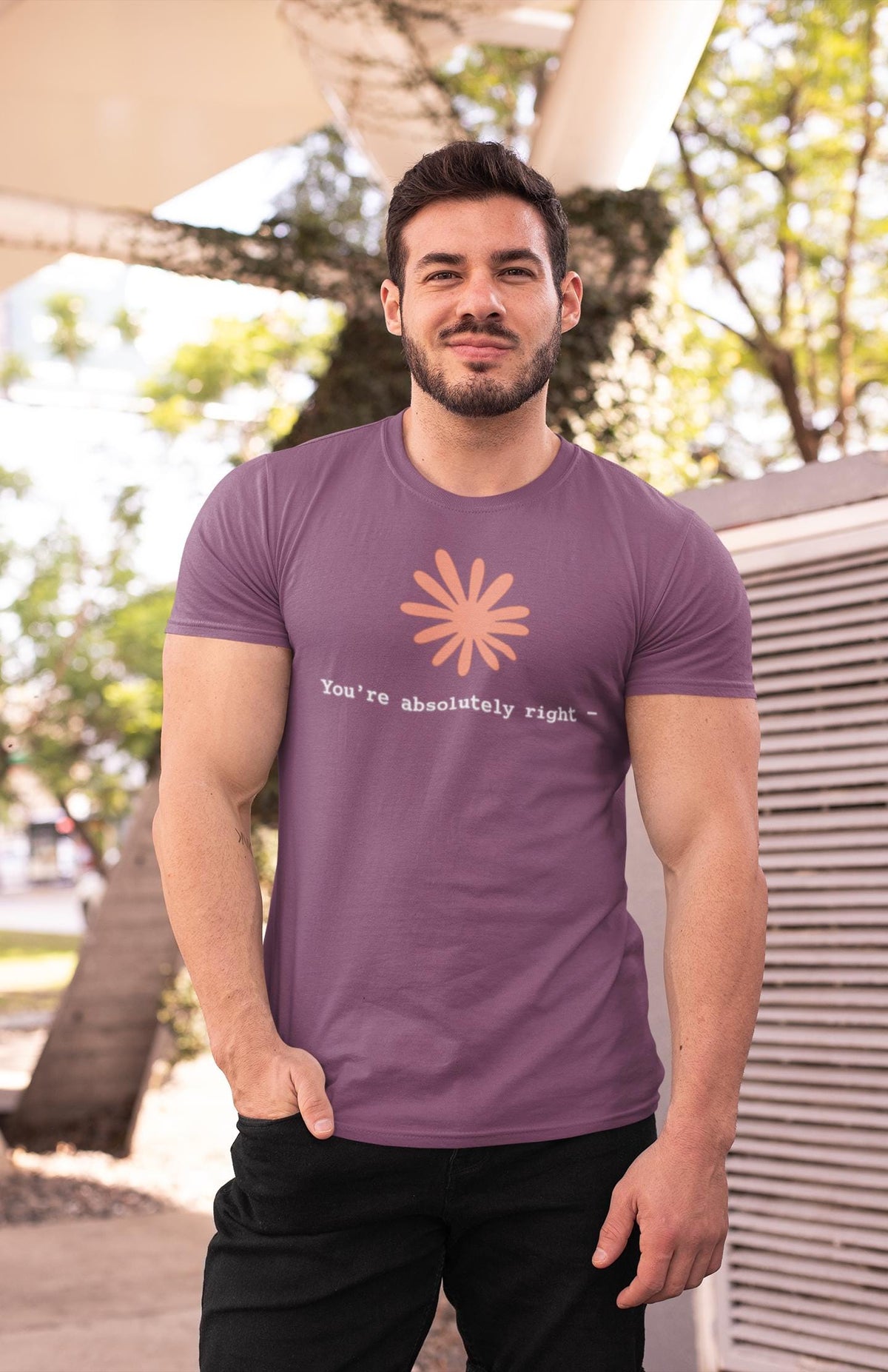 May include: A mauve short-sleeved t-shirt featuring a light peach-colored stylized flower graphic centered on the chest. Below the flower, the text "You're absolutely right -" is printed in a white, typewriter-style font on the fabric.