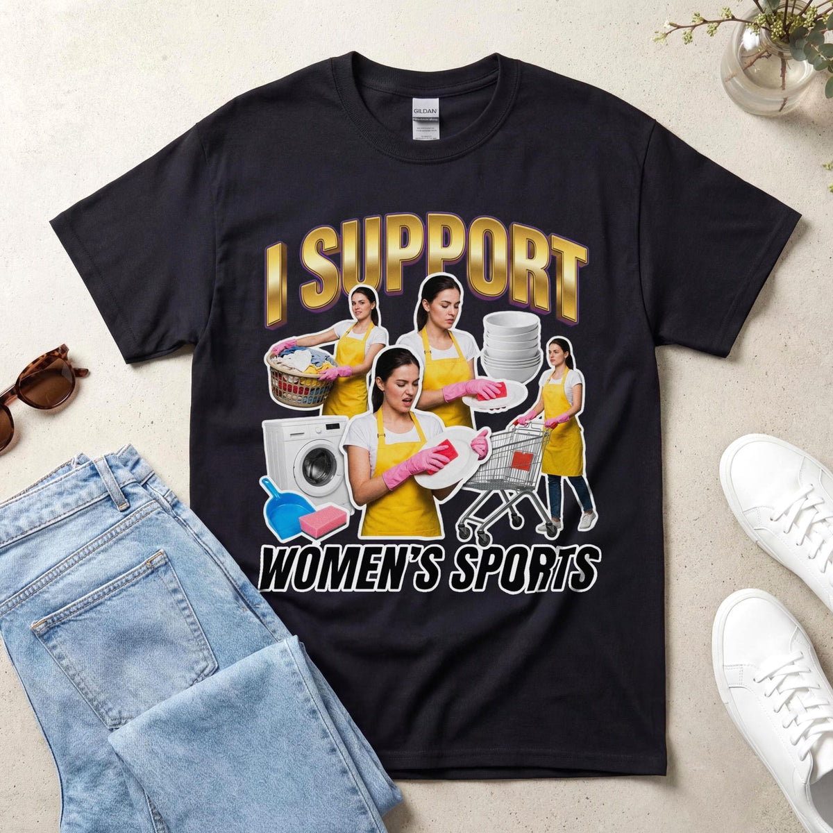 May include: A black t-shirt featuring the text I SUPPORT WOMEN'S SPORTS in gold and white lettering. The graphic includes four images of a person wearing a yellow apron and pink gloves performing household chores like laundry and dishwashing.