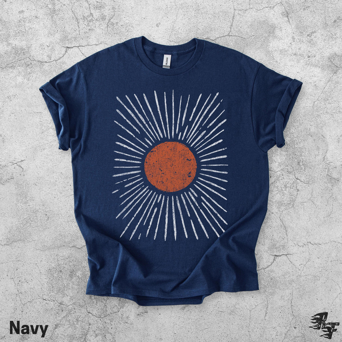 May include: A navy blue short-sleeve t-shirt featuring a central graphic of a distressed, textured orange circle surrounded by radiating white lines that extend outward in a sunburst pattern. The shirt has a crew neckline and a standard fit.
