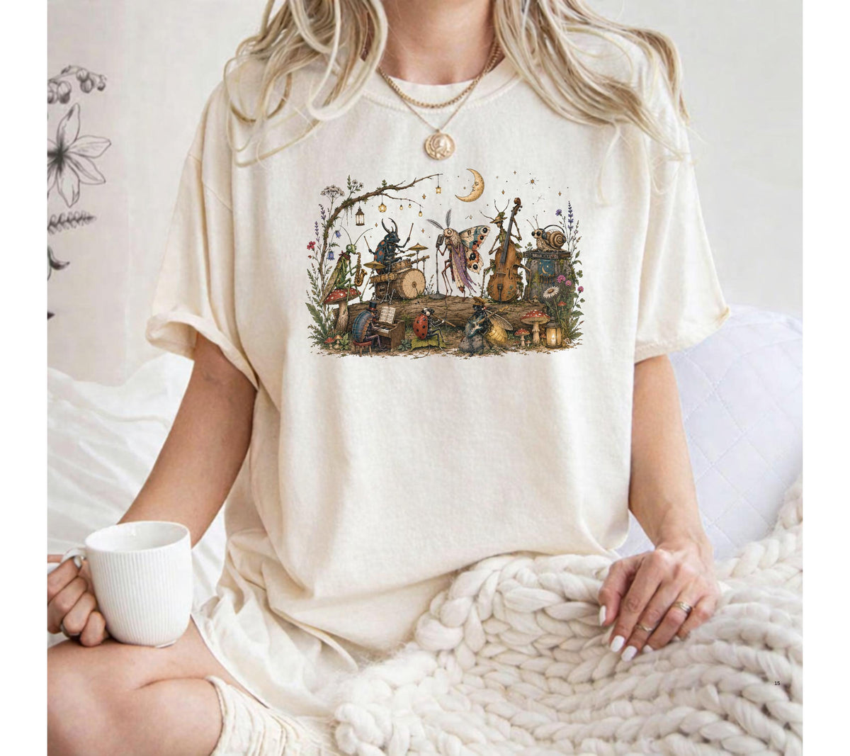 May include: An off-white short-sleeve t-shirt featuring a detailed, colorful graphic print of various insects playing musical instruments in a forest setting, including a beetle on drums, a moth on a cello, and a snail, surrounded by mushrooms.