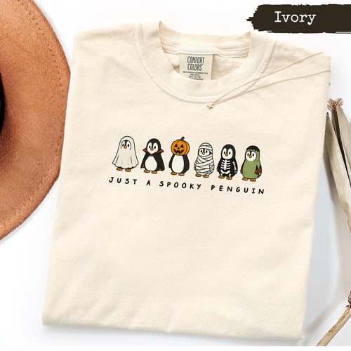 Ivory t-shirt with a Halloween penguin graphic and text "JUST A SPOOKY PENGUIN".