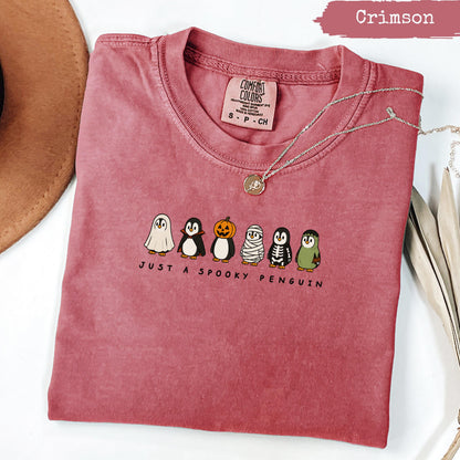 Crimson short-sleeve t-shirt with penguins dressed as ghosts, mummy, and skeleton.