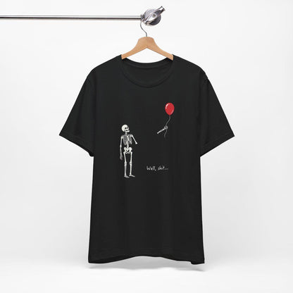 May include: A black short-sleeve t-shirt featuring a white graphic of a skeleton looking at a red balloon floating away with a microphone attached to the string. The text "Well, shit..." is printed in white below the skeleton on the front of the shirt.