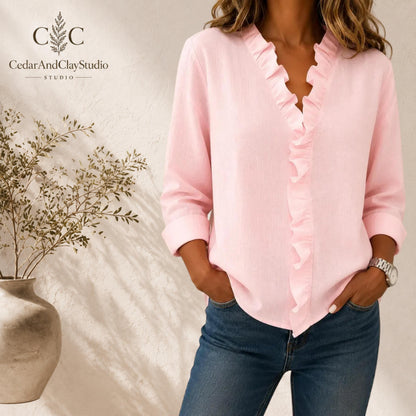 Alt Text
Woman wearing a soft pink ruffle V neck blouse made from lightweight breathable polyester fabric, designed as a casual long sleeve top with a loose boho fit, featuring elegant ruffle detailing along the neckline, styled with blue jeans in a minimalist indoor setting
