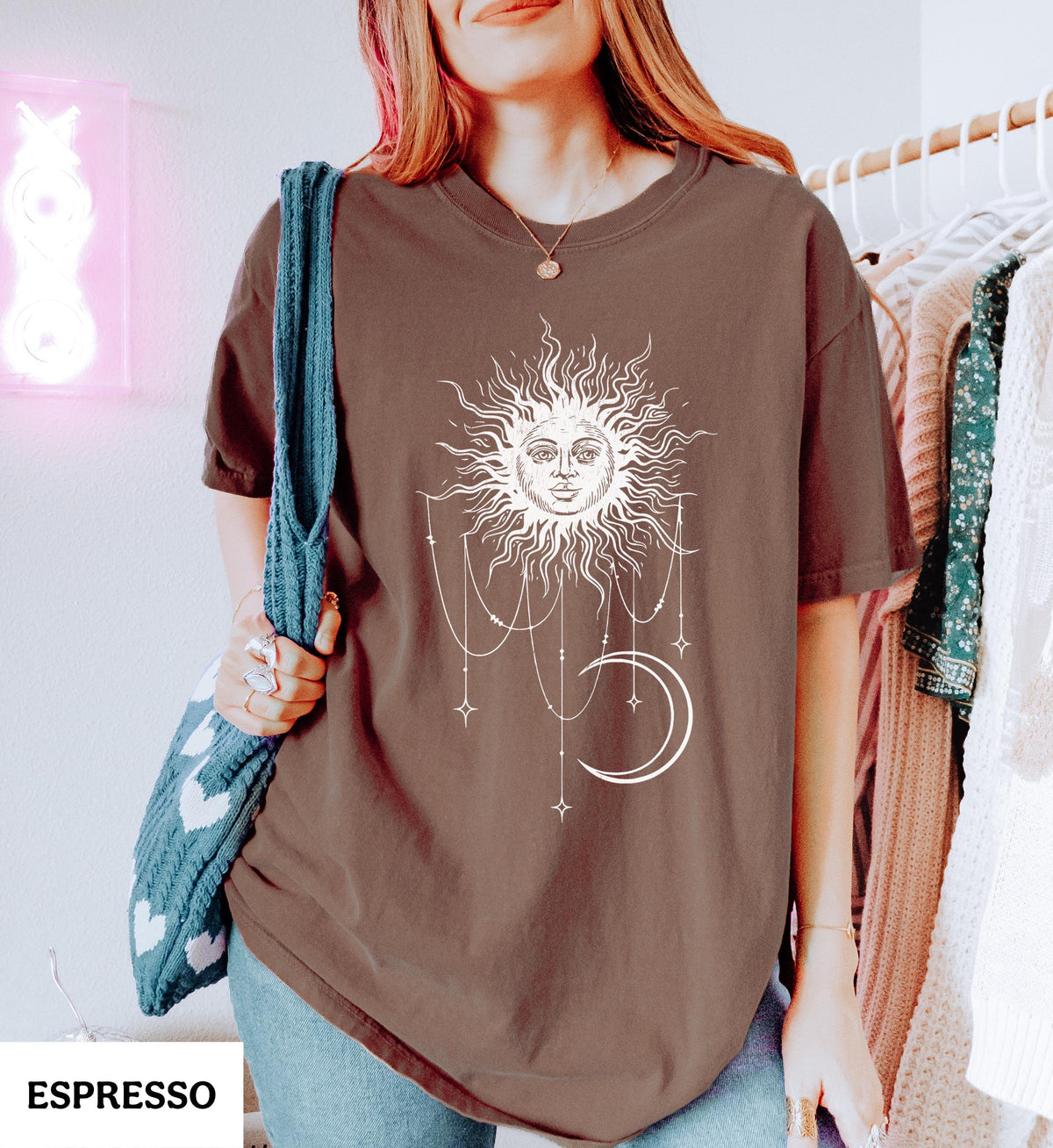 May include: A brown short-sleeve t-shirt featuring a white graphic print of a sun with a face, a crescent moon, and hanging star ornaments. The shirt has a crew neckline and a relaxed fit. The word ESPRESSO is printed in the bottom corner.