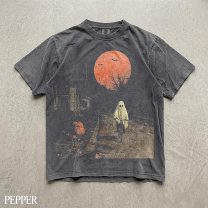 May include: A charcoal gray short-sleeve t-shirt featuring a graphic print of a ghost riding a bicycle under a large orange moon. The design includes silhouettes of bats, bare tree branches, and a pumpkin on a path, with the word PEPPER at the bottom.