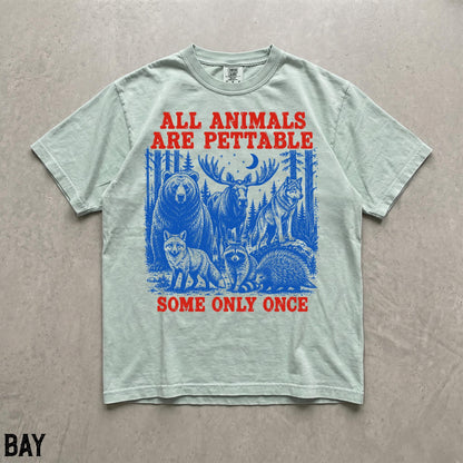 May include: A light green short-sleeve t-shirt featuring a blue graphic of a bear, moose, wolf, fox, raccoon, and porcupine in a forest. The text in red reads ALL ANIMALS ARE PETTABLE SOME ONLY ONCE. The shirt has a crew neckline and a relaxed fit.
