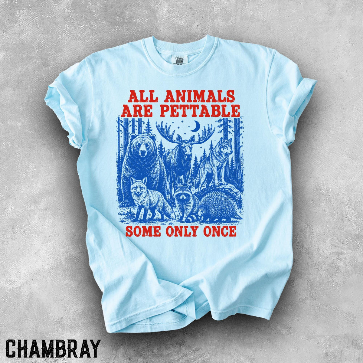 May include: A light blue t-shirt featuring a graphic print of a bear, moose, wolf, fox, raccoon, and porcupine in a forest setting. The red text reads ALL ANIMALS ARE PETTABLE at the top and SOME ONLY ONCE at the bottom of the illustration.
