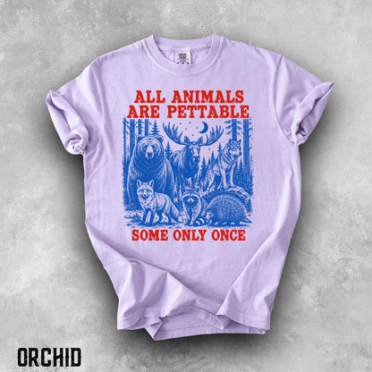 May include: A light purple short-sleeve t-shirt featuring a blue graphic of a bear, moose, wolf, fox, raccoon, and porcupine in a forest. The red text reads ALL ANIMALS ARE PETTABLE at the top and SOME ONLY ONCE at the bottom of the graphic.