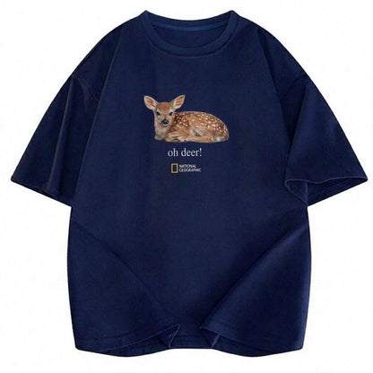 May include: A navy blue short-sleeve t-shirt featuring a graphic of a spotted fawn lying down. Below the fawn, the text reads "oh deer!" followed by the National Geographic logo. The shirt has a crew neckline and a relaxed, loose-fitting silhouette.