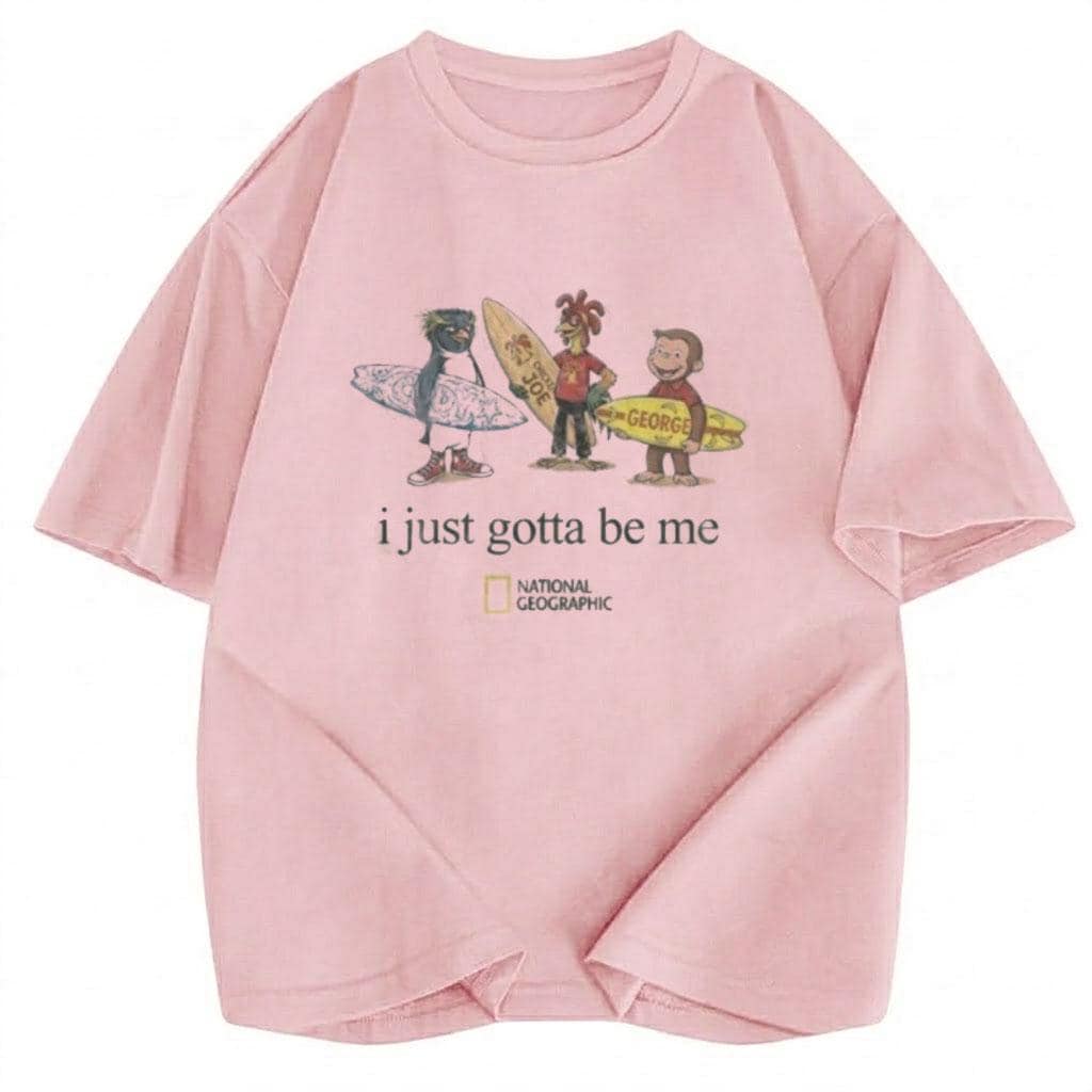 May include: A light pink short-sleeve t-shirt featuring a graphic of three cartoon characters holding surfboards. Below the characters is the text "i just gotta be me" and the National Geographic logo. The shirt has a crew neckline and a relaxed fit.