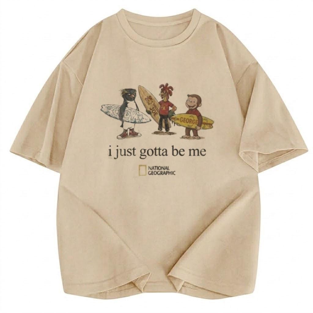 May include: A beige short-sleeved t-shirt featuring a graphic of a penguin, a chicken, and a monkey holding surfboards. Below the characters, the text reads "i just gotta be me" followed by the National Geographic logo in black and yellow.