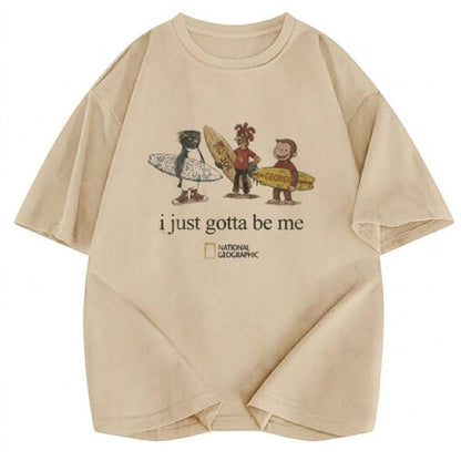 May include: A beige short-sleeved t-shirt featuring a graphic of a penguin, a chicken, and a monkey holding surfboards. Below the characters, the text reads "i just gotta be me" followed by the National Geographic logo in black and yellow.