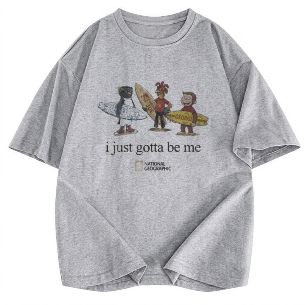 May include: A heather gray short-sleeve t-shirt featuring a graphic of three cartoon characters holding surfboards. Below the characters, the text reads "i just gotta be me" followed by the National Geographic logo in a yellow rectangular box.