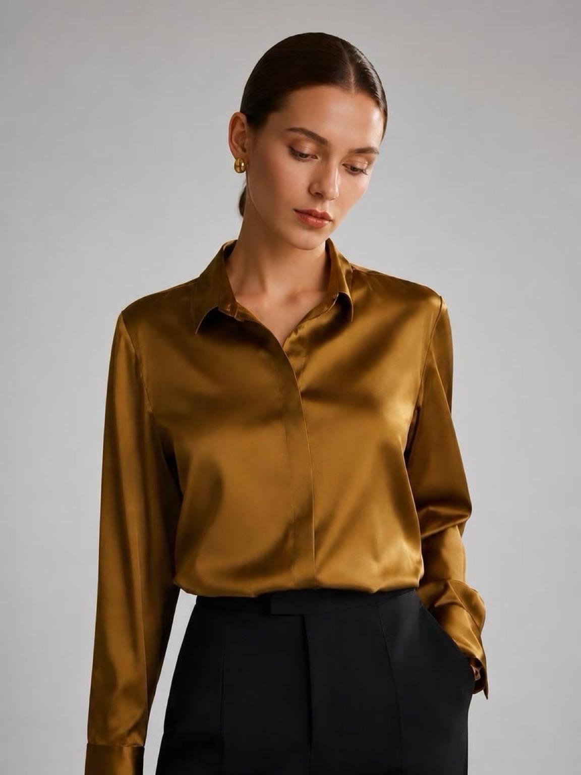 May include: A long-sleeved button-down shirt in a metallic bronze-gold satin fabric with a pointed collar and a concealed front placket, paired with black trousers. The shirt features a smooth, reflective finish and structured cuffs.