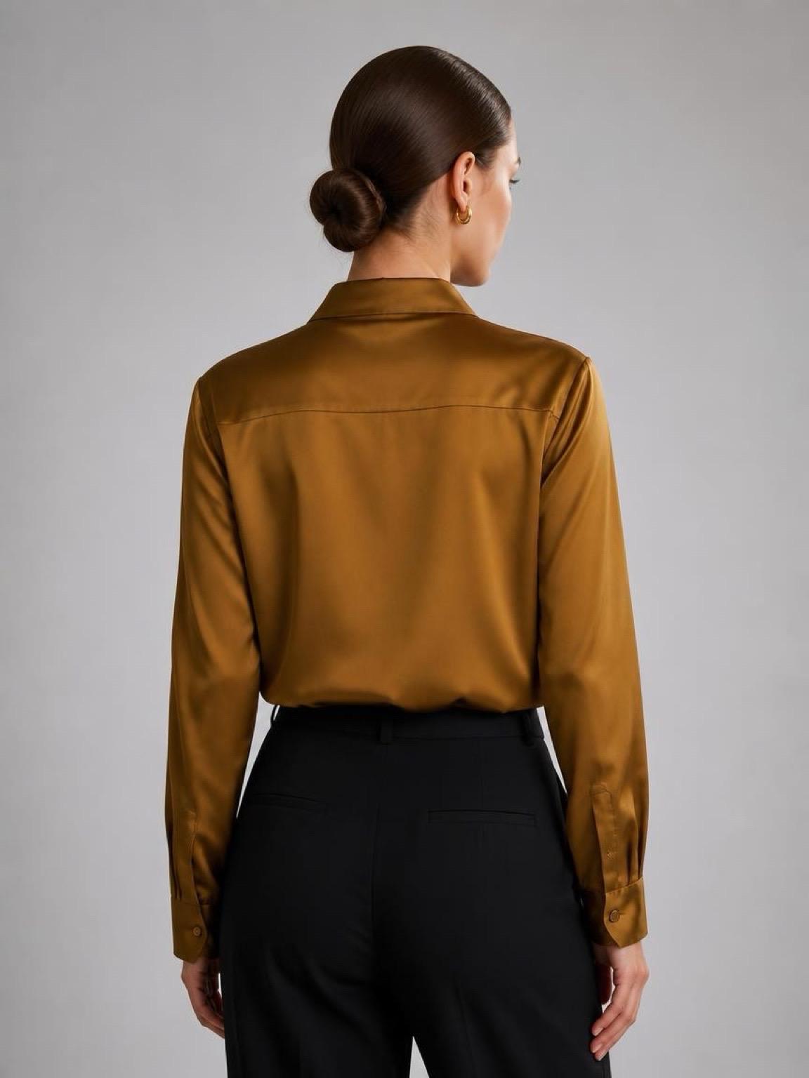 May include: A long-sleeved button-down shirt in a lustrous mustard gold satin fabric, featuring a classic collar, a back yoke, and buttoned cuffs, paired with solid black trousers. The shirt has a smooth, reflective finish and a tailored fit.