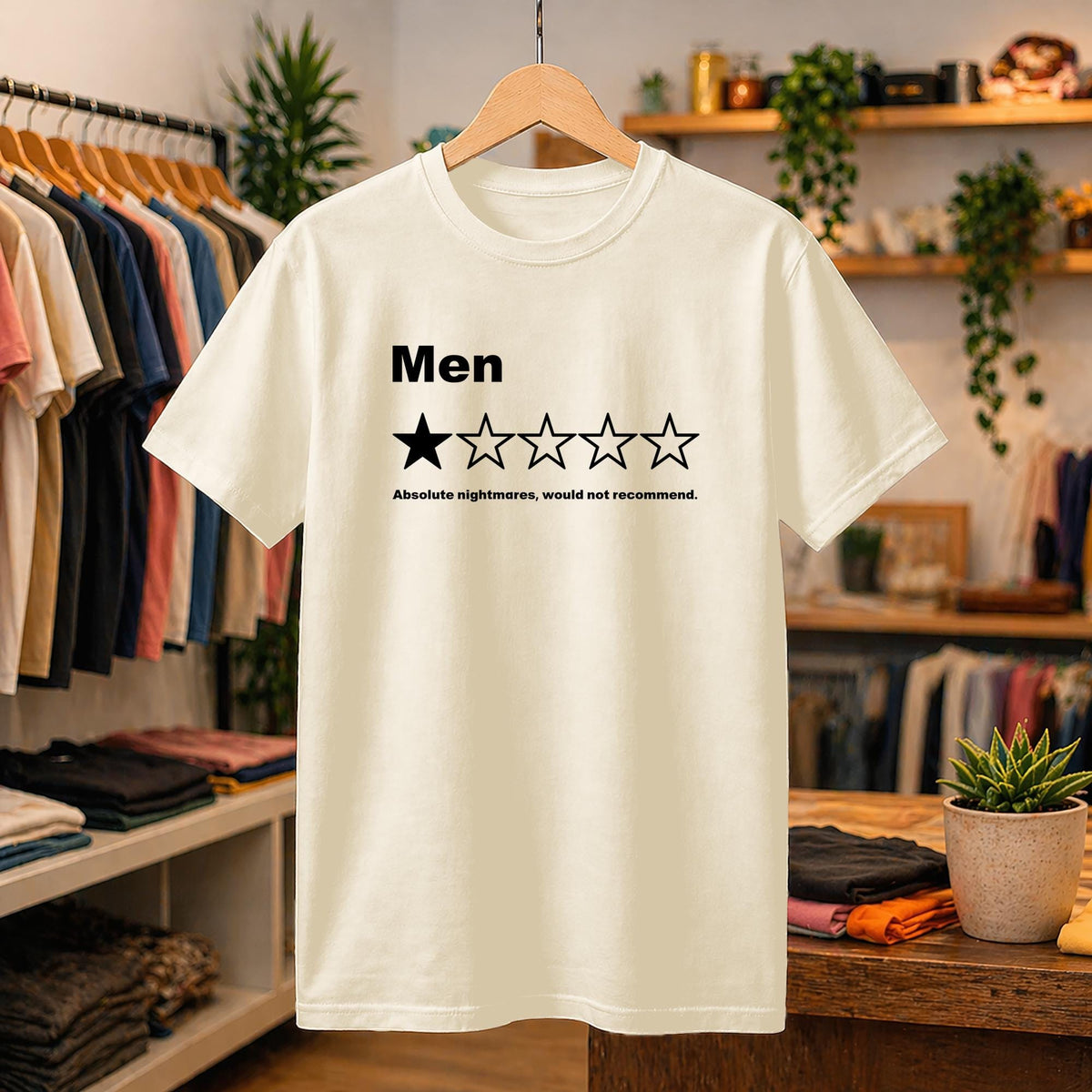 May include: A cream-colored short-sleeve t-shirt featuring the black text 'Men' above a five-star rating graphic with only one star filled in. Below the stars, the black text reads 'Absolute nightmares, would not recommend.'