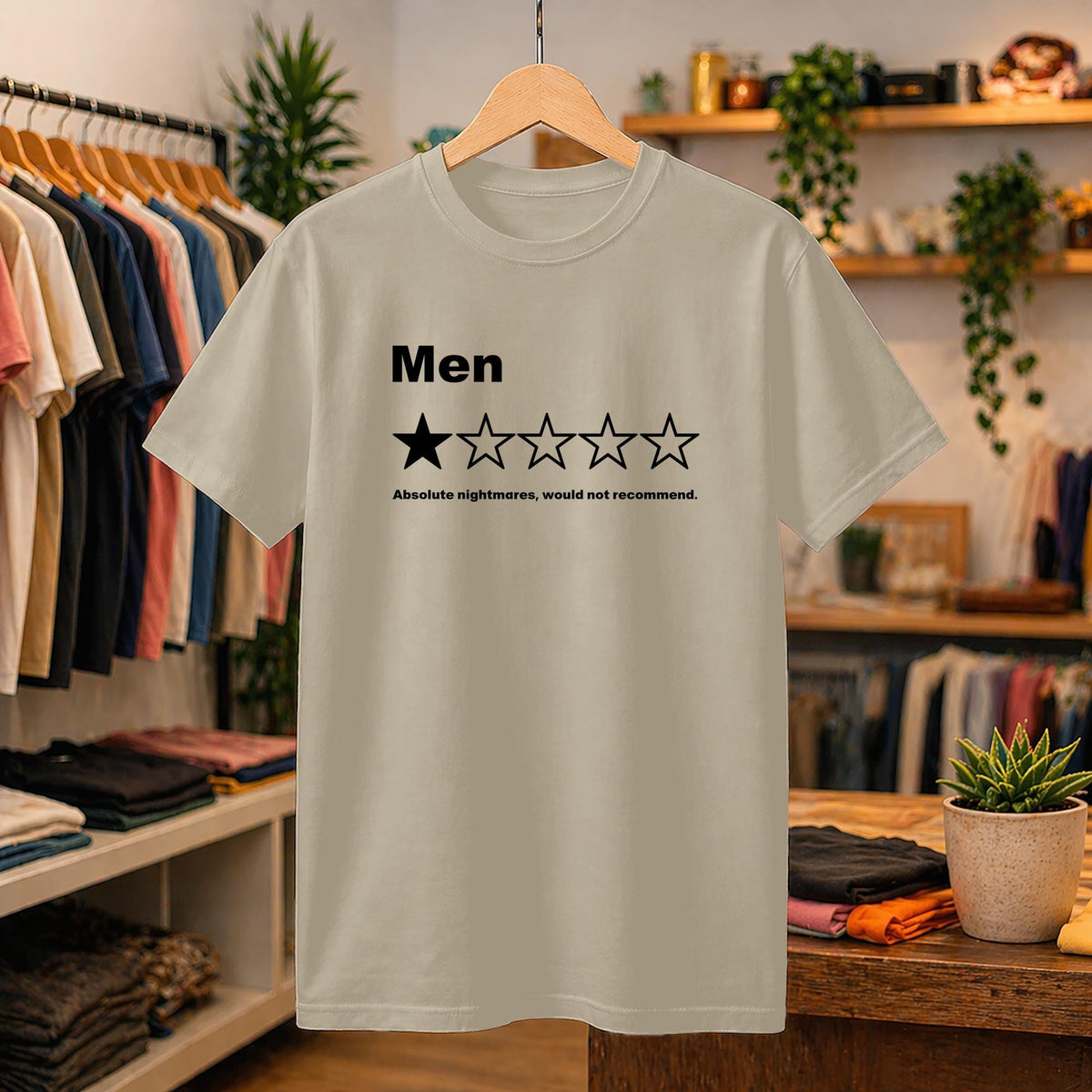 May include: A beige short-sleeved t-shirt featuring the black text 'Men' above a five-star rating graphic with one filled-in star and four empty stars, followed by the text 'Absolute nightmares, would not recommend.' printed in black.