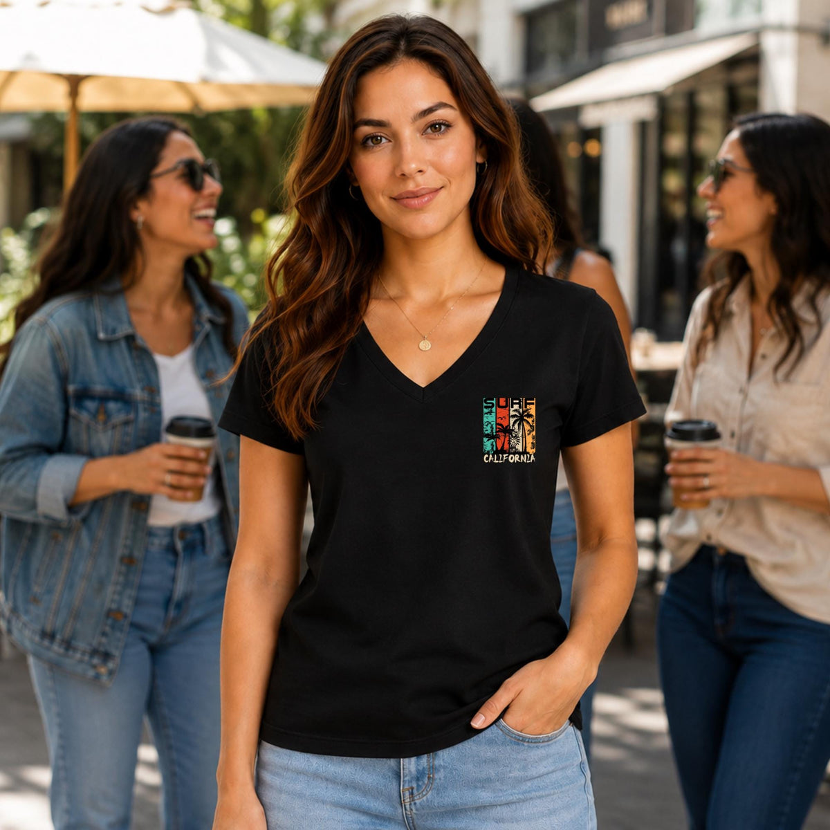 May include: A black V-neck t-shirt featuring a small, rectangular graphic on the left chest. The graphic displays a sunset-colored design with palm trees and the text "SURF CALIFORNIA" in a stylized font, set against a dark background.